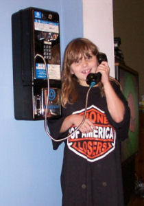 Emily uses a pay phone while wearing her new shirt.